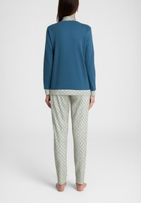 Pigiama in cotone composto da una maglia a maniche lunghe blu e pantaloni verde-beige a fantasia con un motivo a griglia diagonale.