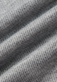 Szary materiał o teksturowanym wzorze w kratę houndstooth, z różnymi odcieniami szarości, podkreślający głębię dzięki swoim miękkim, splecionym włóknom.