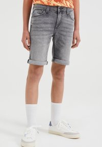 Pantalones cortos de mezclilla gris con dobladillos enrollados, que cuentan con un diseño de cinco bolsillos y un acabado ligeramente desgastado, combinados con zapatillas blancas y calcetines de canalé.