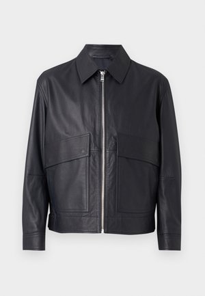 Mustast nahkjakist kraega, ees pingutuslukk ja kaks suurt rinnataskut. Sujuv tekstuur ja kohandatud korrigeeritud lõige.