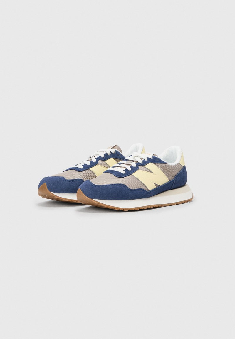 Blauwe en beige sportieve schoenen met een bovenwerk van suede, gaasaccenten en witte veters. Voorzien van een gevoerde zool met een lichtbruine profiel.