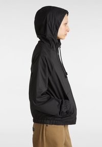 Giacca leggera nera con cappuccio, con polsini e orlo elasticizzati, dotata di tasca frontale e cappuccio con cordino, texture liscia e design minimale.