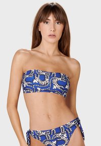 Top bikini bandeau blu e bianco con motivo a fantasia e parte inferiore con lacci laterali coordinati. Presenta forme astratte e una texture liscia ed elastica.