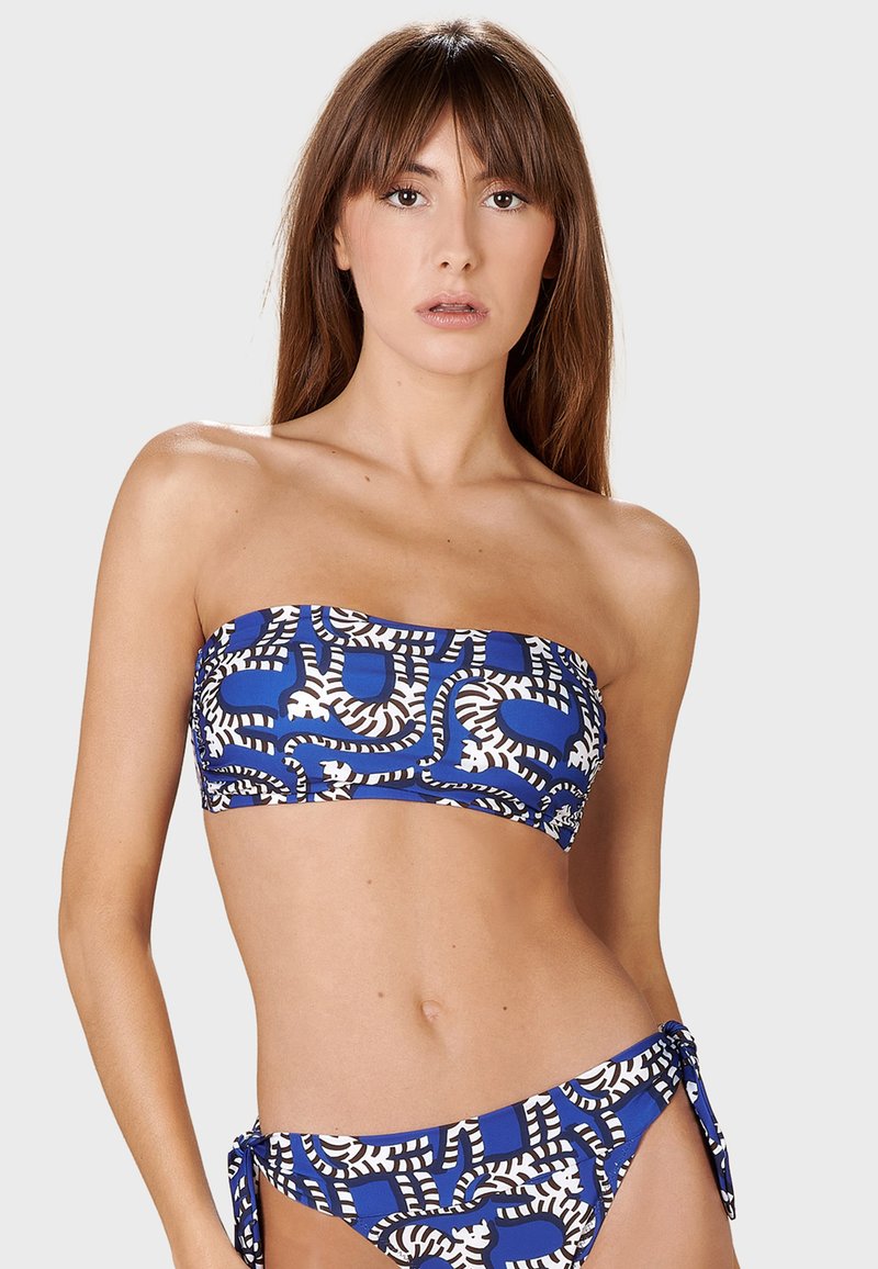 Top bikini bandeau blu e bianco con motivo a fantasia e parte inferiore con lacci laterali coordinati. Presenta forme astratte e una texture liscia ed elastica.