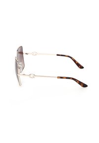 Lunettes de soleil à monture dorée avec des verres à dégradé marron et des branches aux embouts à motif écaille, sur fond blanc.