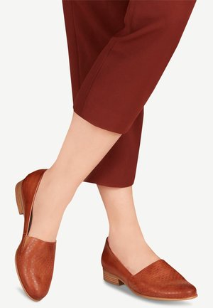 Chaussures slip-on en cuir marron avec une surface texturée et un petit talon en bois, présentant un bout arrondi et un design supérieur lisse et large.