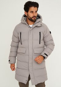 Hellgrauer, wattierter Mantel mit Kapuze. Verfügt über Reißverschlusstaschen auf der Brust und Fronttaschen mit Klappen. Glatte Textur mit dunklen Akzenten an den Reißverschlüssen.