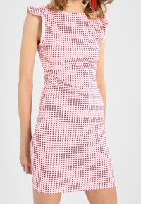 Robes en vichy rouge et blanc avec des manches courtes, silhouette cintrée et longueur au-dessus du genou. Présente une texture tissée lisse et un motif ludique.