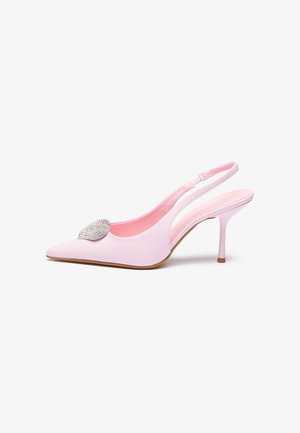 Jasnoróżowy sandał na obcasie typu slingback z cienką szpilką, z ostro zakończonym noskiem i błyszczącą kryształową ozdobą z przodu na białym tle.