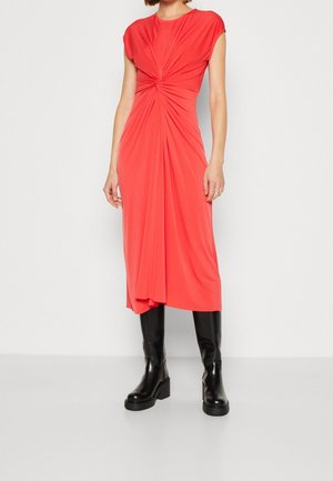 Vestido midi de color coral con mangas tipo farol, que presenta un diseño retorcido en la cintura, combinado con botas de tacón cuadrado negras. Textura de tela suave.