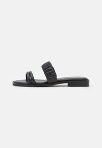 Zwarte platte sandalen met twee dunne banden en een gerimpelde bovenband. Gemaakt van glad materiaal, met een minimalistisch ontwerp en een lage zool.