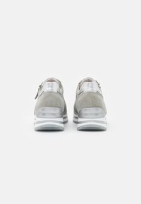 Harmaat mokkasukat hopeakuvioilla, pehmeällä kauluksella ja valkoisella kerroksellisella pohjalla. Molemmilla puolilla on vetskarihelma, joka helpottaa pukemista.