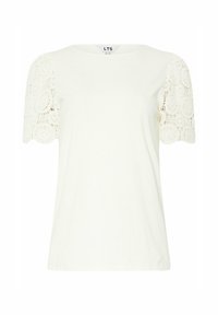 T-shirt blanc avec un col rond, manches courtes en dentelle, présentant un motif circulaire et des détails texturés sur les manches.