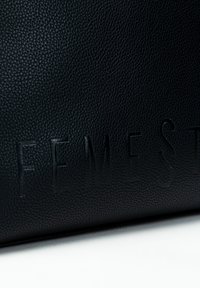 Zwarte leren tas met een gestructureerd oppervlak en het geponste "FEMEST" logo. Heeft een gladde afwerking met een lichtgestreept uiterlijk.