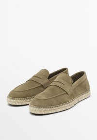 Mockasiner i mocka i olivgrön färg med en upphöjd sömdesign och en espadrillestil jutesula. Slät textur och bekväm slip-on stil.