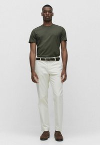 Oliven grøn kortærmet t-shirt, hvide lige bukser, vævet mørkt bælte og brune sko. Enkel, afslappet outfits uden mønstre.