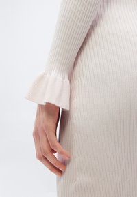 Ριμπ πλεκτό ροζ φόρεμα με φουσκωτά μανίκια και εφαρμοστή γραμμή, με εμφανείς ραφές και ομαλή υφή.