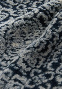 Tessuto tessile con un motivo a vortice in blu scuro e grigio chiaro. Texture morbida con una finitura pelosa, caratterizzata da accenti intricati.