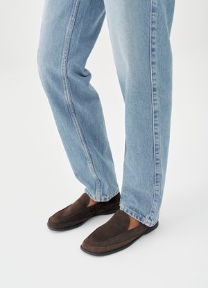 Hnedé semišové slip-on topánky s hladkou textúrou, s okrúhlou špičkou a minimálnym prešívaním, doplnené svetlomodrými rifľami.