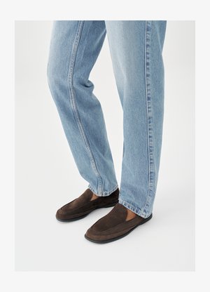 Bruine suède instapschoenen met een gladde textuur, voorzien van een afgeronde neus en minimale stiksels, gecombineerd met lichtblauwe spijkerbroek.