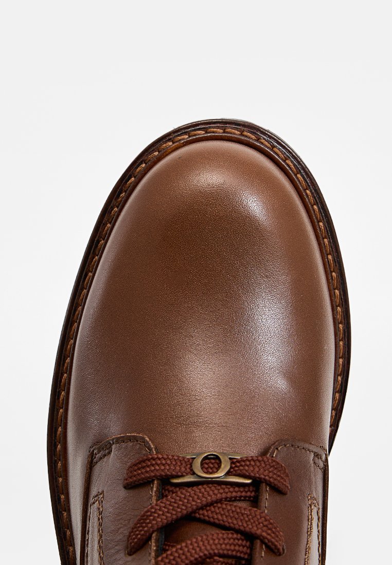 Braune Lederschuhe mit glatter Textur, abgerundetem Zeh und kontrastierenden braunen Schnürsenkeln. Mit dekorativen Nähten entlang der Kante.