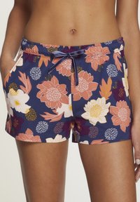 Bloemenprint shorts met een marineblauwe achtergrond, met roze, witte en gele bloemen. Elastische tailleband met een trekkoord en zakken.