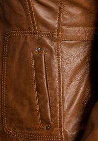 Bruine leren jas met een gestructureerd oppervlak, uitgerust met een grote patchzak en contrasterende stikdetails. Inclusief zwarte drukknoopaccenten.