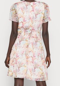 Blumenkleid aus transparentem Material in zarten Farbtönen. Verfügt über kurze Ärmel, eine taillierte Taille und einen ausgestellt Rock mit subtiler Textur.