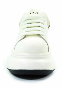 Białe sneakersy z grubą podeszwą, sześcioma otworami na sznurowadła, zaokrąglonym czubkiem i częściowo widocznym logo marki na wyściełanym języku.