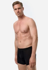 Boxer briefs neri con una cintura morbida che presenta un testo con il logo. Il materiale appare liscio con un design aderente, adatto per l'uso quotidiano.