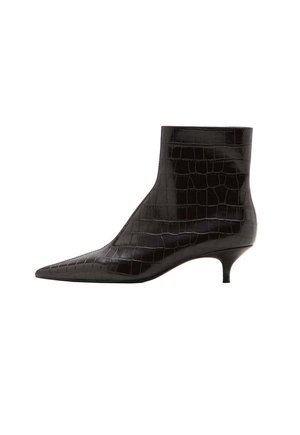 Botín negro con puntera puntiaguda, tacón bajo tipo kitten y textura brillante de cocodrilo sobre superficie de cuero suave.