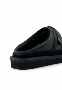 Zwarte slipper met een zachte binnenvoering, met een ronde vorm en een bovenkant van zacht textiel. Stevige zwarte rubberen zool, gladde textuur, minimale accenten.