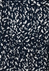 Marineblauwe stof met een wit abstract patroon bestaande uit verschillende vormen. Het ontwerp bevat plooien aan de bovenkant voor textuur en beweging.