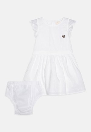 Rochie albă din bumbac cu mâneci volănașe, broderie florală și o aplicație în formă de inimă; asortată cu pantaloni scurți albi.