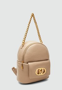 Zaino in pelle beige con forma arrotondata, tracolla in catena dorata, chiusura con zip e tasca frontale con accento logo in metallo dorato.