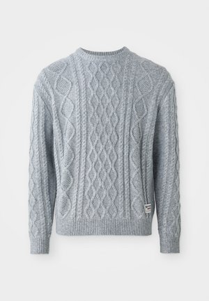 Pull en maille grise avec un motif en câble, col rond et poignets et ourlet côtelés. Présente une petite étiquette sur le côté inférieur gauche.