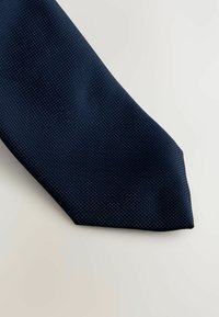 Marineblauer Krawatte mit strukturiertem Muster, an der Spitze verjüngt, aus einem Stoff mit dezentem erhöhtem Design. Glatte Oberfläche.