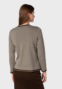 Stickad tröja med ett diagonalt randmönster i brunt och kräm, rund hals och kontrasterande fåll. Accentuerad med ribbade ärmslut.