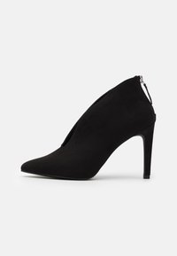 Botines de tacón alto en ante negro con punta afilada y cierre de cremallera en la parte posterior, que presentan una textura suave y un diseño elegante.