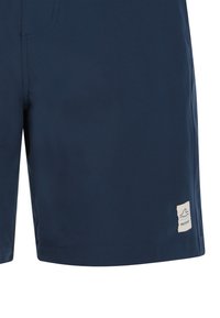 Shorts de bain bleu marine en tissu léger, avec un petit patch logo sur le bas et une texture lisse.
