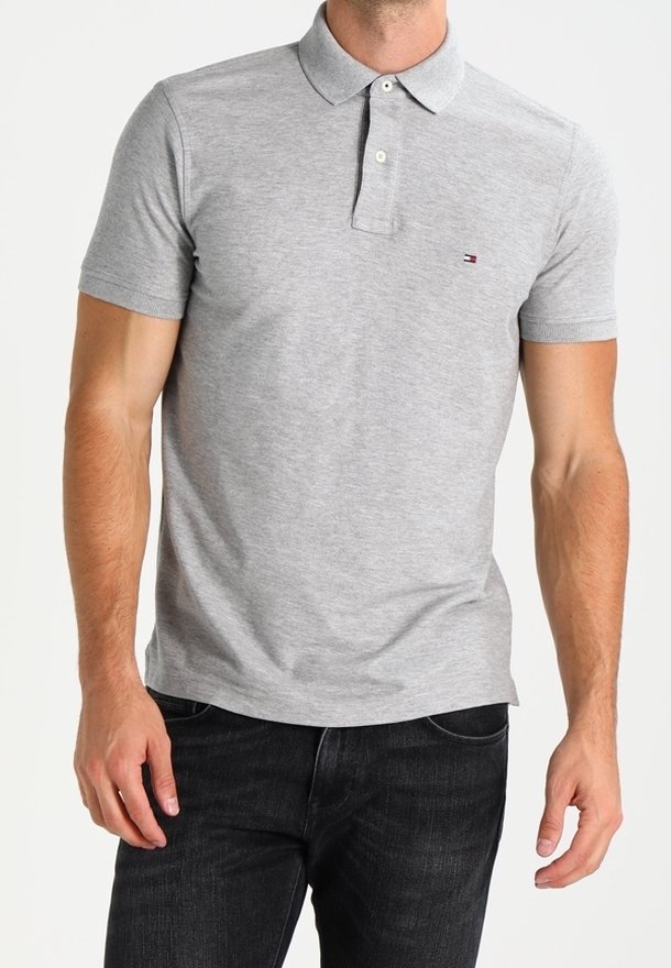 Grå polo skjorte lavet af bomuld, med en klassisk krave, to-knaps lukning og et lille logo på venstre bryst. Båret sammen med mørke jeans.