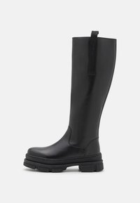 Černé kozačky po kolena vyrobené z hladké kůže, s tlustou texturovanou podešví a poutkem na zadní straně pro snadné obutí.