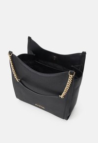 Czarna skórzana torebka na ramię z złotym łańcuszkiem, otwarta u góry, ukazująca pikowane wnętrze i zapięcie magnetyczne.