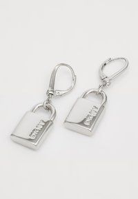 Silver lock-shaped earrings with a polished finish and a leverback clasp, featuring embossed branding on the surface.