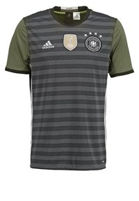 Šedý atletický dres s proužky a zelenými rukávy, zdobený vyšívanými logy a odznakem. Vyrobený z lehké látky s pohodlným střihem.