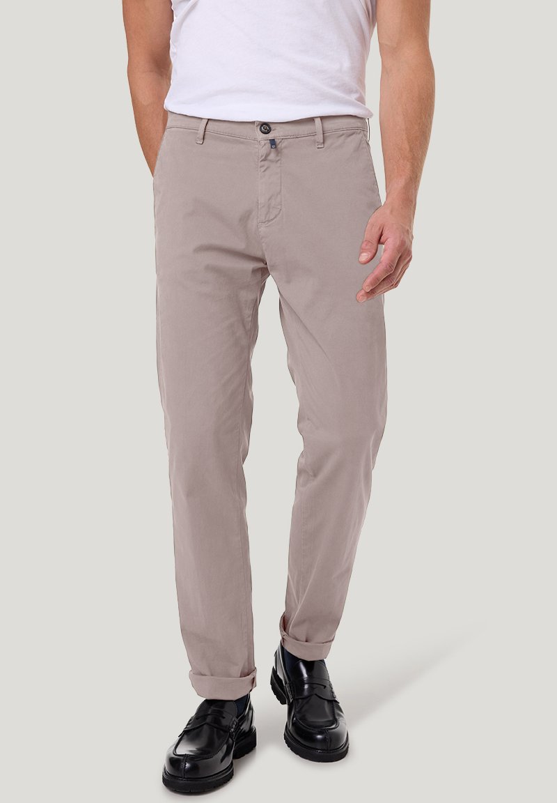 Beige katoenen broek met een rechte pasvorm, voorzien van een knoopsluiting en opgerolde manchetten, gecombineerd met zwarte leren schoenen.