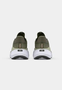 Oliwkowe buty sportowe z teksturowanej tkaniny, z kontrastową białą podeszwą i gumowym bieżnikiem. Zawierają logo PUMA i pętle do zakupu.