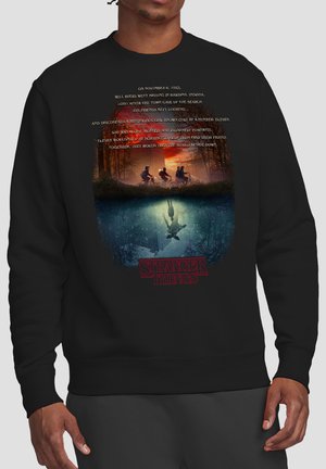 Four kids riding bikes at sunset over a reflective water scene showing a girl with outstretched arms and Stranger Things text below.