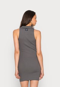 Vestido cinza canelado sem mangas com colarinho e ajuste justo, apresentando uma etiqueta de logotipo nas costas. Textura suave, design até ao joelho.