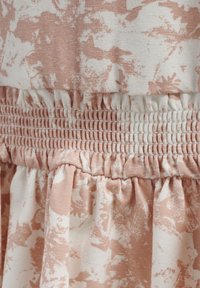 Rosa och vit blommönstrad tyg med smockad midja; mjuk textur med veckad kjol och elastisk midjeresår.